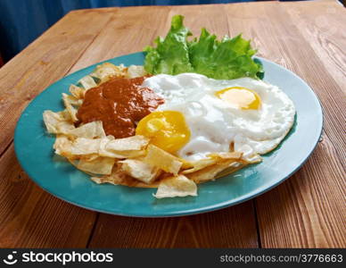 Huevos con chilaquiles - Mexican traditional breakfast eggs. Eggs with tortilla chips topped with red sauce.