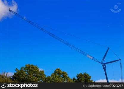 Huge crane above trees with blue sky
