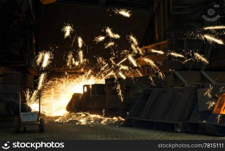 Huge drill creating a pouring hole in an industrial furnace - sparks flying everywhere