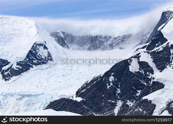 Huge glacier in black rock cauldron from high mountain range near south pole