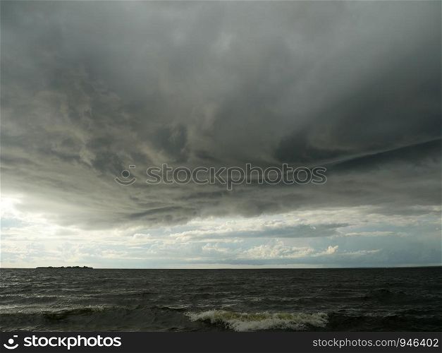 huge low dark clouds approaching the shore from the sea