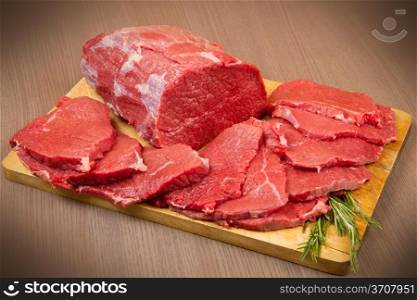 huge red meat chunk and steak on wood table