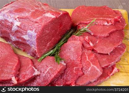 huge red meat chunk and steak on wood table
