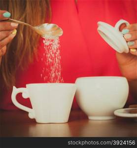 Human adding sugar to tea or coffee.. Closeup of human adding sugar to tea or coffee at home. Person with hot beverage relaxing in kitchen.