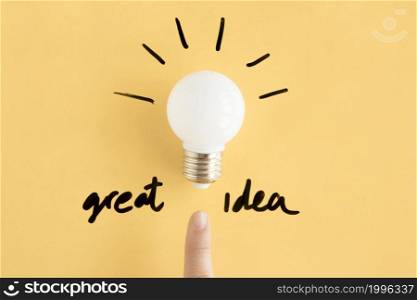 human finger pointing towards light bulb with great idea text