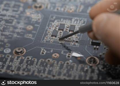 Human fingers making repair of motherboard. Close-up photo