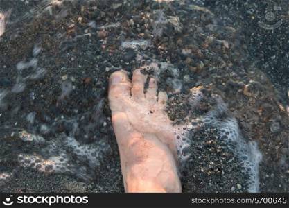 Human foot in water on the beach, Trout River, Gros Morne National Park, Newfoundland and Labrador, Canada