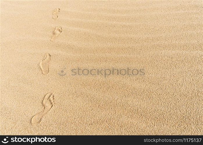Human footsteps on yellow fine sand, on a sunny day of summer, on Sylt island, at North Sea, Germany. Footprints on a sandy beach. Summer wandering.