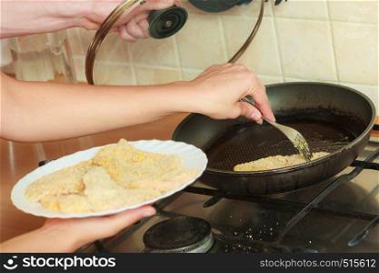 Human frying breaded chicken cutlet on fry pan. Person making dinner meal.