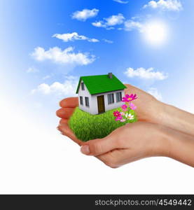 Human hand against blue sky background and house