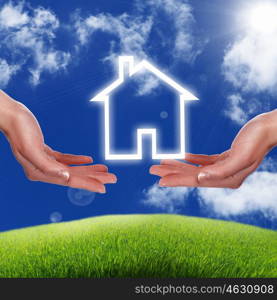 Human hand against blue sky background and house