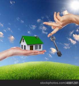 Human hand against blue sky background and house