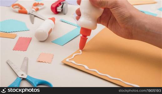 human hand applying white glue orange paper with scissor stapler. Beautiful photo. human hand applying white glue orange paper with scissor stapler