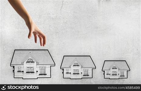 Human hand grabs drawn on paper house. Hand picking home