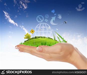 human hand holding a city on green grass hill