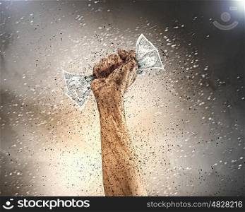 Human hand holding dollar banknote. Close-up of human hand in dirt clenching dollar banknote