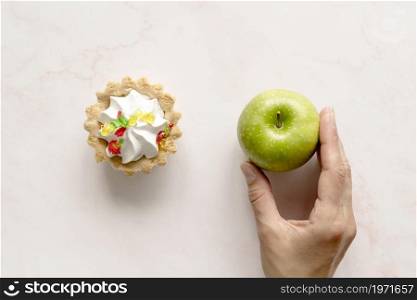 human hand holding green apple near tart cake backdrop. High resolution photo. human hand holding green apple near tart cake backdrop. High quality photo
