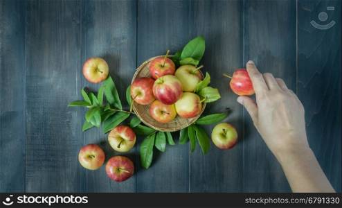 human hand holding red and yellow apple on wooden background , Top view