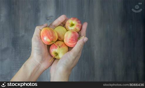 human hand holding red and yellow apple on wooden background , Top view