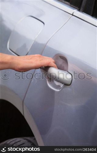 Human hand holding silver car door handle, opening doors going into vehicle.. Human hand holding car door handle