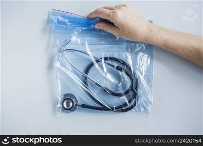 human hand holding zip lock plastic bag with stethoscope