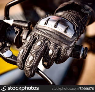 Human hand in a Motorcycle Racing Gloves holds a motorcycle throttle control. Hand protection from falls and accidents.