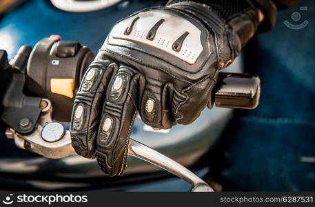 Human hand in a Motorcycle Racing Gloves holds a motorcycle throttle control. Hand protection from falls and accidents.