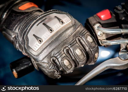 Human hand in a Motorcycle Racing Gloves holds a motorcycle throttle control. Hand protection from falls and accidents.