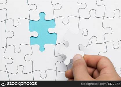 human hand inserting white puzzle empty space. High resolution photo. human hand inserting white puzzle empty space. High quality photo