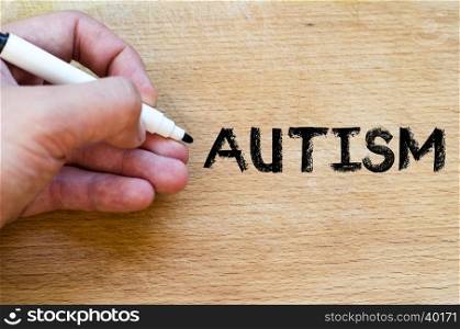 Human hand over wooden background and autism text concept