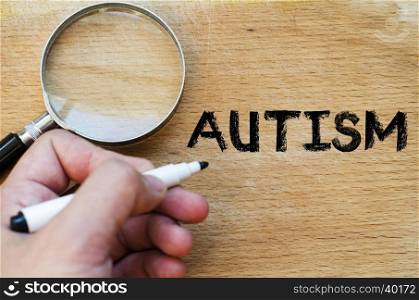 Human hand over wooden background and autism text concept