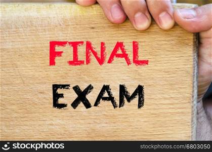 Human hand over wooden background and final exam text concept
