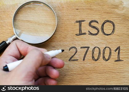 Human hand over wooden background and iso 27001 text concept