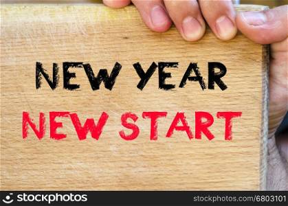 Human hand over wooden background and new year new start text concept
