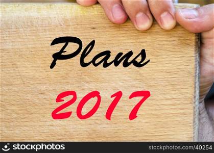 Human hand over wooden background and plans 2017 text concept