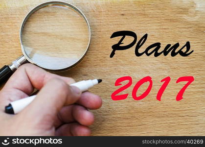 Human hand over wooden background and plans 2017 text concept