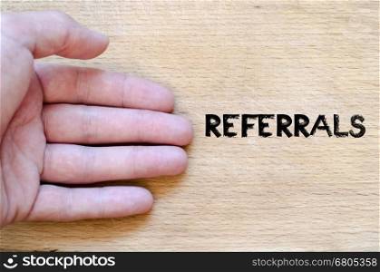 Human hand over wooden background and referrals text concept