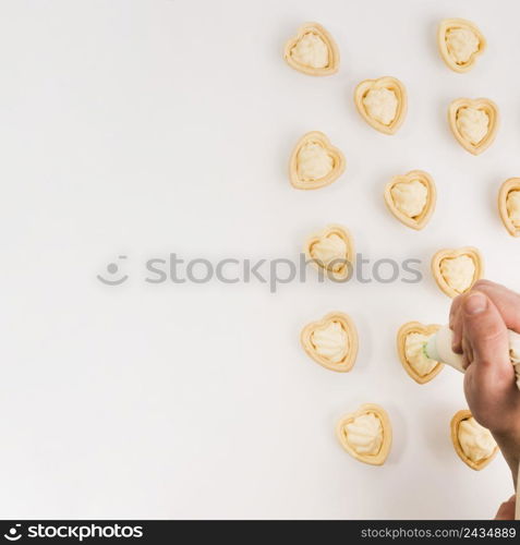 human hand putting fresh cream yummy heart shape tartlet