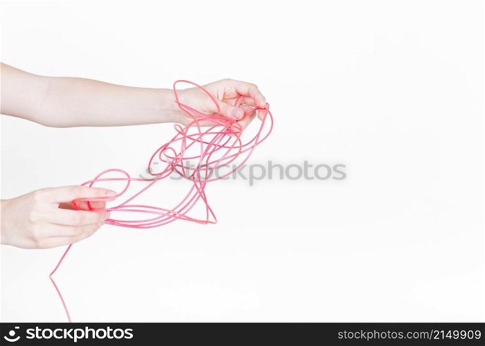 human hand trying untangle red wire white background