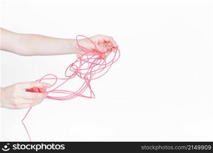 human hand trying untangle red wire white background