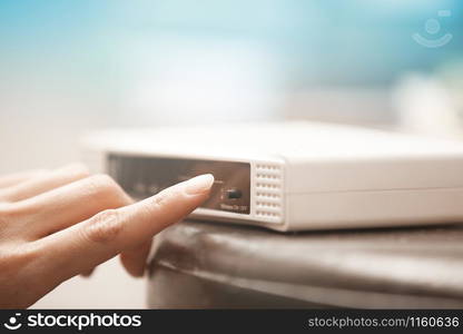 Human hand turning on wireless modem. Close-up horizontal photo