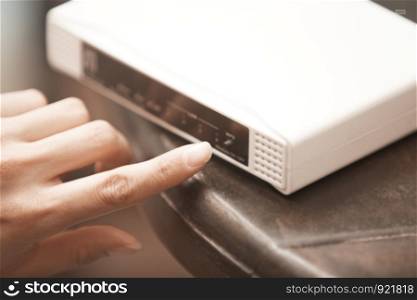 Human hand turning on wireless modem. Close-up horizontal photo