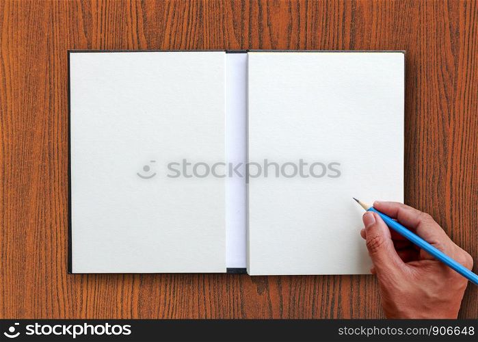 Human hand use blue pencil to write open notebook put on brown wooden tabletop with white space for texts or something display