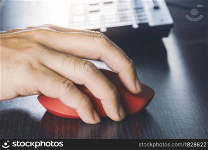 Human hand using computer mouse with a red color on desk