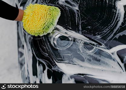 Human hand work concept. Man washes car with soap and cloth. Vehicle cleaning. Close up shot of hand mop washing automobile