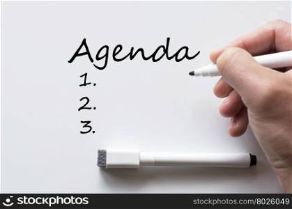 Human hand writing agenda on whiteboard