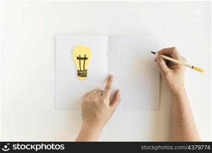 human hand writing card with light bulb