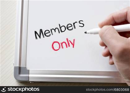 Human hand writing members only on whiteboard
