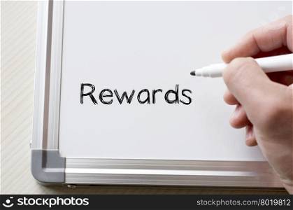 Human hand writing rewards on whiteboard