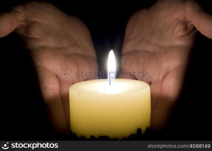 Human hands and candle in the night